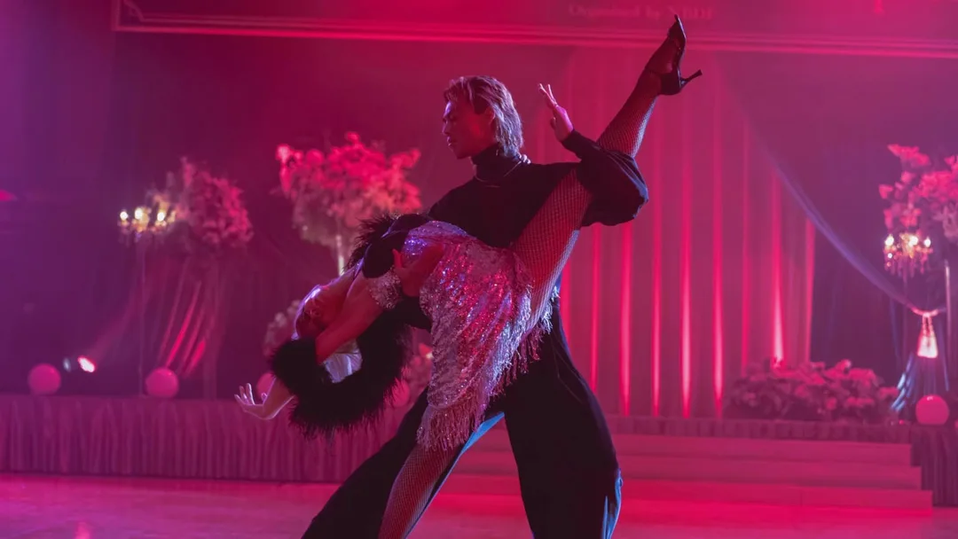 Zwei Männer in Tanzhaltung stehen sich intensiv gegenüber, die Stirnen nah beieinander, in eleganter Ballroom-Kleidung.