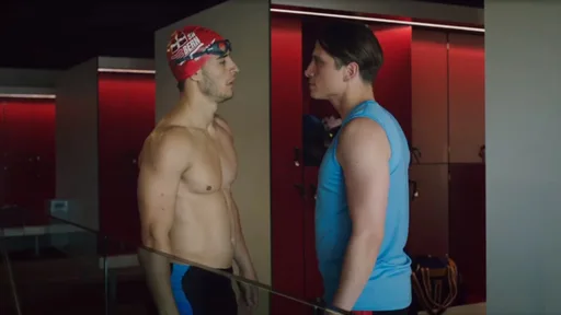 Junger Mann in Sportkleidung blickt nachdenklich zur Seite, im Hintergrund Schwimmbecken