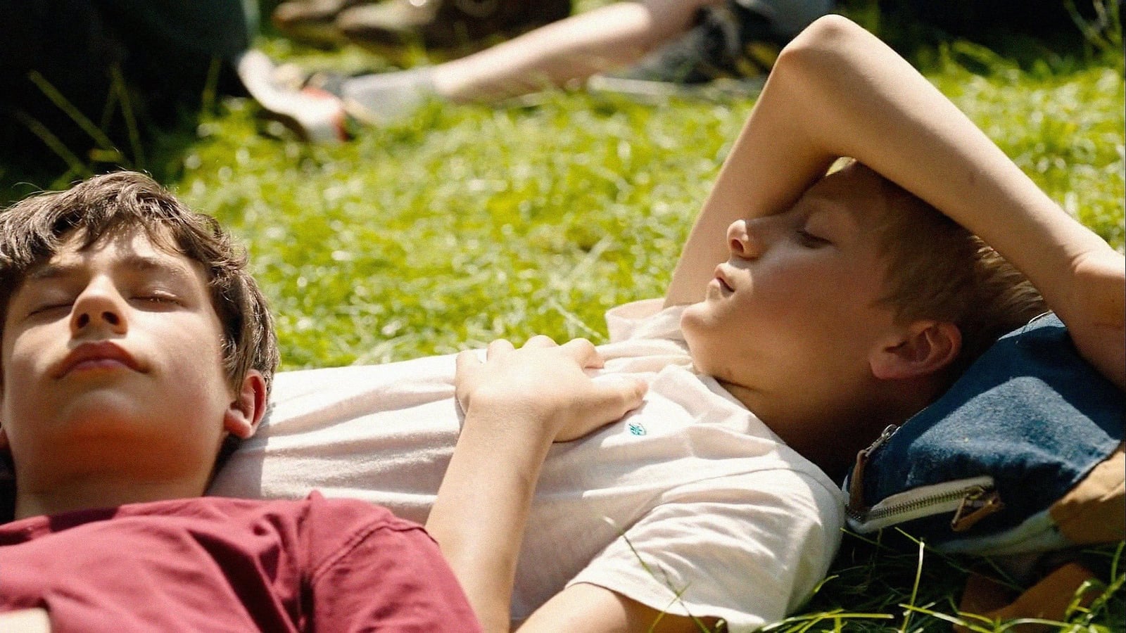 Zwei 13-jährige Jungen liegen eng umschlungen in einem Blumenfeld in Close (2022)
