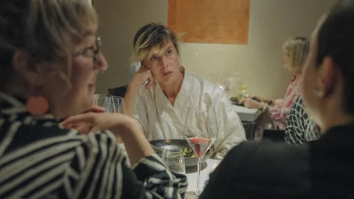 Zwei Schwestern stehen in einem norddeutschen Haus und blicken sich angespannt an, während im Hintergrund ihre Mutter wartet. Filmszene aus Donkey Days von Rosanne Pel.