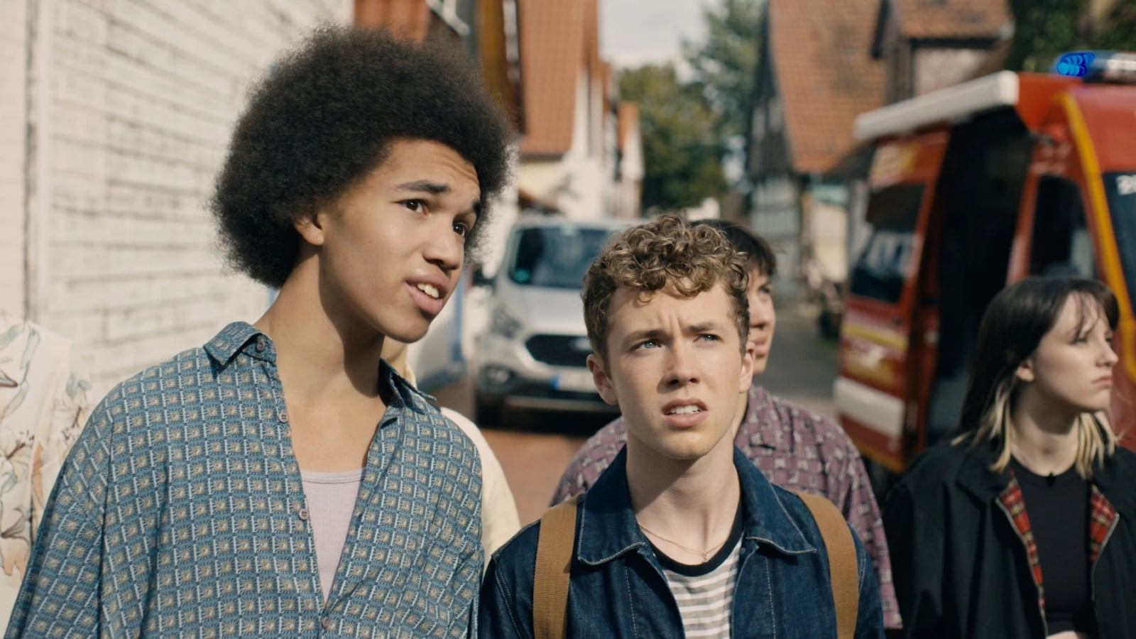 Zwei junge Männer sitzen nebeneinander in ländlicher Umgebung, ernste Gesichter, intensive Blicke, aus dem Film Free at Heart.