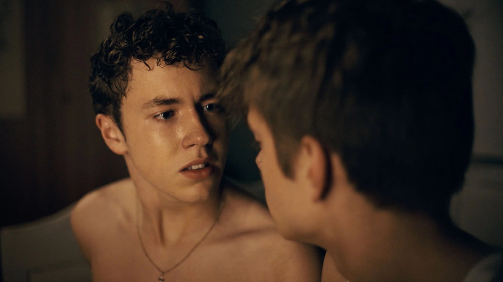 Zwei junge Männer sitzen nebeneinander in ländlicher Umgebung, ernste Gesichter, intensive Blicke, aus dem Film Free at Heart.