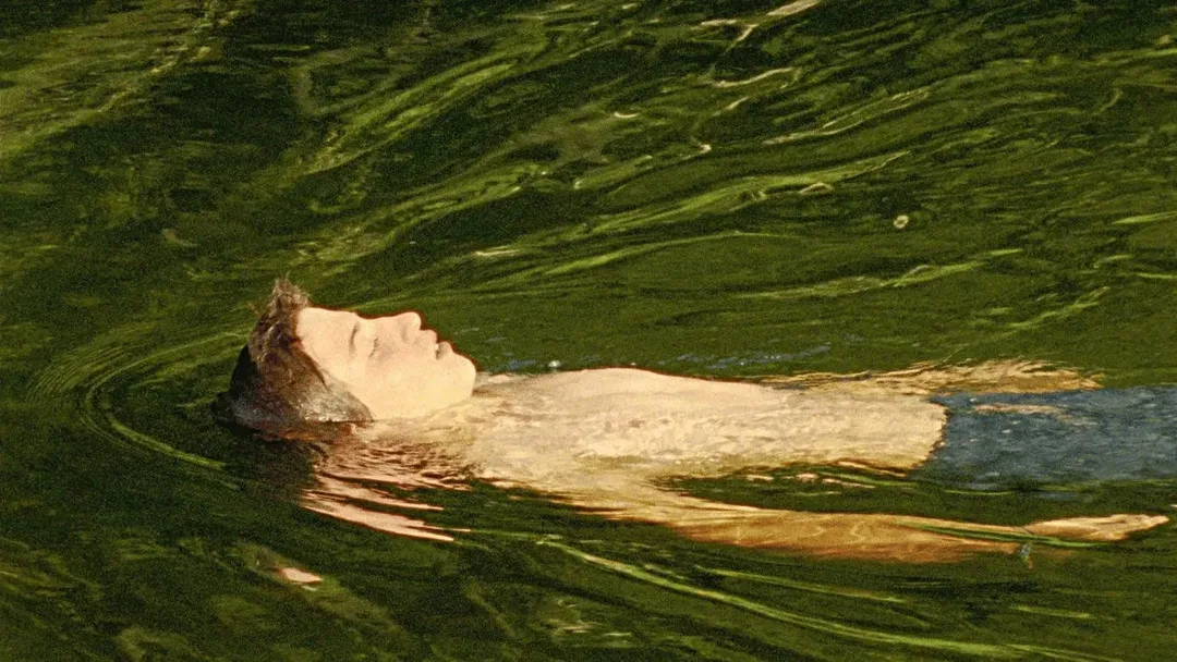 Teenager Dídac schwimmt in der Donau, Nahaufnahme seines nachdenklichen Gesichts im klaren Wasser, 16mm Film-Ästhetik mit übersättigten Grün- und Blautönen