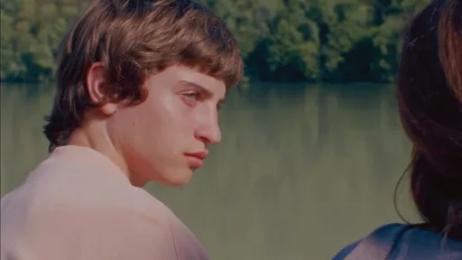 Teenager Dídac schwimmt in der Donau, Nahaufnahme seines nachdenklichen Gesichts im klaren Wasser, 16mm Film-Ästhetik mit übersättigten Grün- und Blautönen